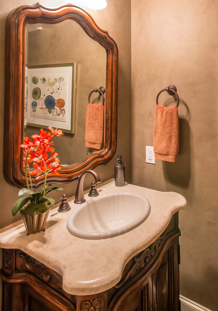 Mid-sized traditional powder room in Dallas with a drop-in sink, furniture-like cabinets, dark wood cabinets, limestone benchtops, beige tile, stone tile, brown walls and travertine floors.