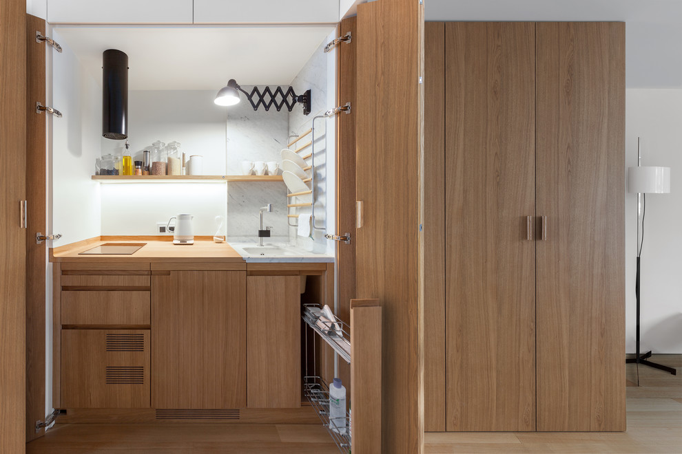 Small contemporary separate kitchen in Moscow with an undermount sink, medium wood cabinets, wood benchtops, white splashback, panelled appliances and medium hardwood floors.