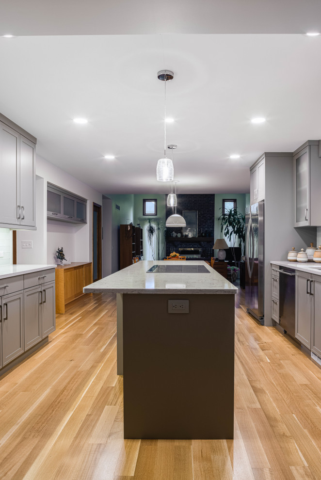 Medium sized classic galley kitchen/diner in Detroit with white splashback, stainless steel appliances, an island, white worktops, shaker cabinets, a submerged sink, grey cabinets, engineered stone countertops, glass tiled splashback, medium hardwood flooring and beige floors.