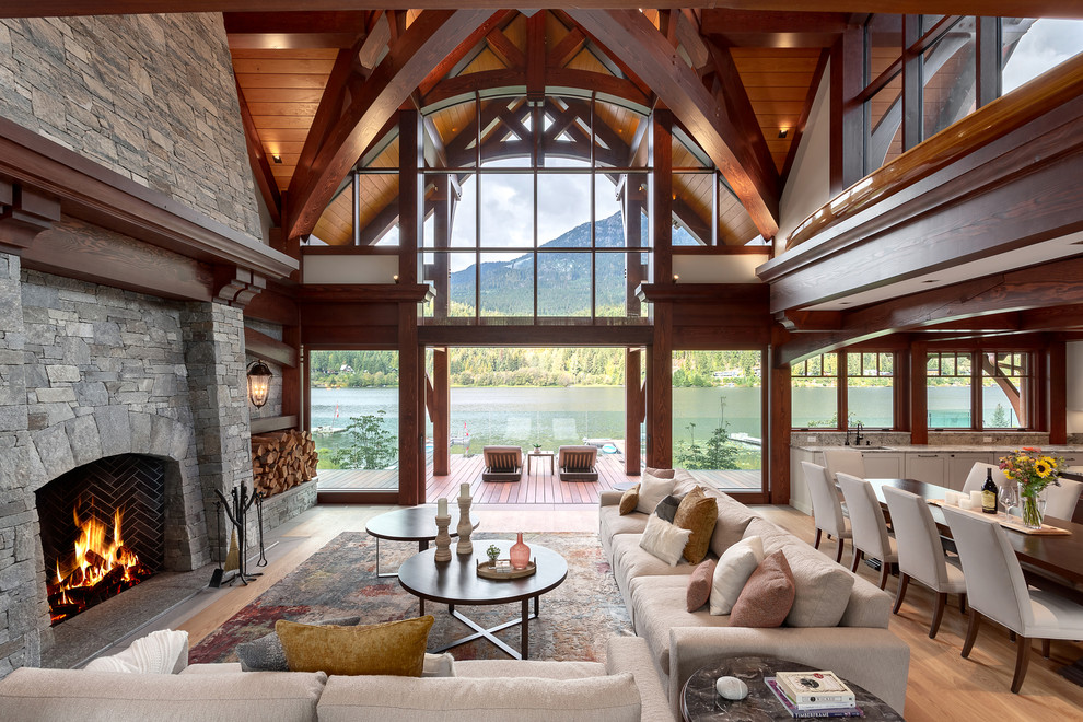 This is an example of a country open concept living room in Other with medium hardwood floors, a standard fireplace, a stone fireplace surround and brown floor.