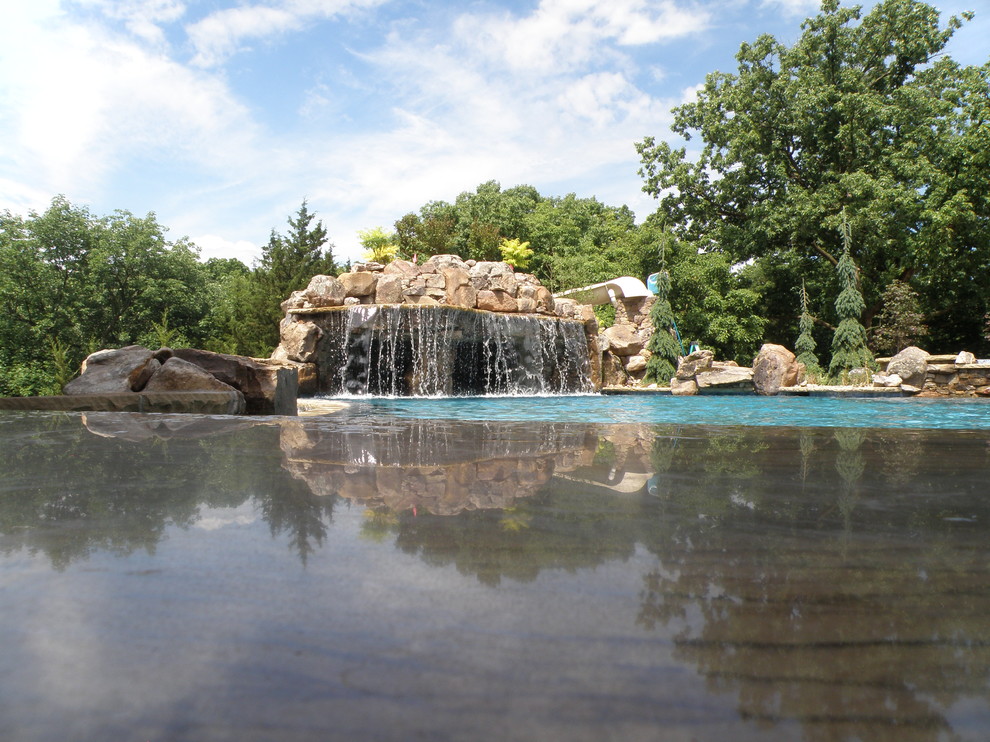 Design ideas for a large arts and crafts backyard custom-shaped pool in Kansas City with a water feature.