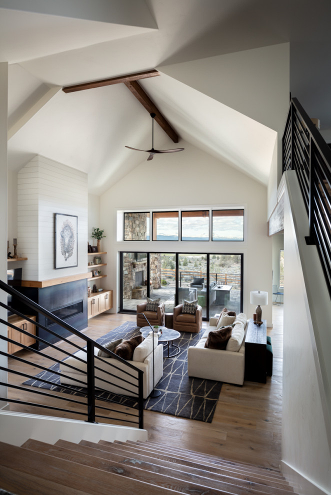 Inspiration for an expansive open plan living room in Portland with white walls, light hardwood flooring, a standard fireplace, a metal fireplace surround, a vaulted ceiling and tongue and groove walls.