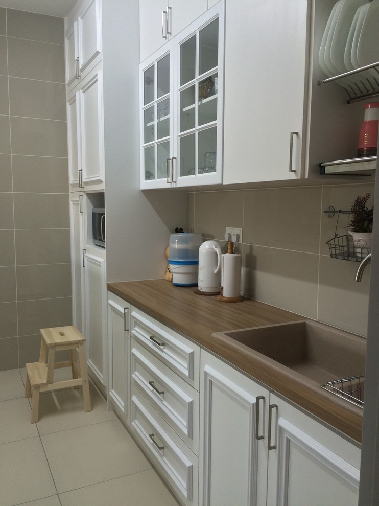 Photo of a mid-sized traditional single-wall eat-in kitchen in Other with a double-bowl sink, beaded inset cabinets, white cabinets, wood benchtops, beige splashback, mosaic tile splashback, black appliances, ceramic floors and with island.