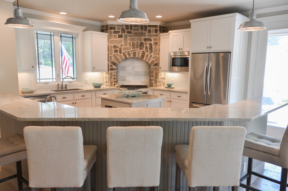 Inspiration for a large country l-shaped open plan kitchen in Portland with beaded inset cabinets, white cabinets, with island, a single-bowl sink, granite benchtops, white splashback, subway tile splashback, stainless steel appliances, light hardwood floors and beige floor.