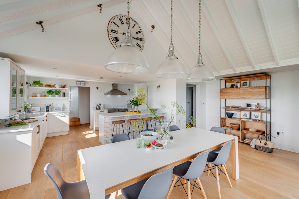 Photo of a scandinavian kitchen/dining combo in Devon with white walls and light hardwood floors.