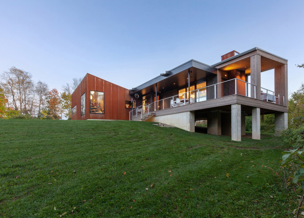 Пример оригинального дизайна: одноэтажный, оранжевый частный загородный дом среднего размера в стиле модернизм с облицовкой из металла, односкатной крышей, металлической крышей и серой крышей