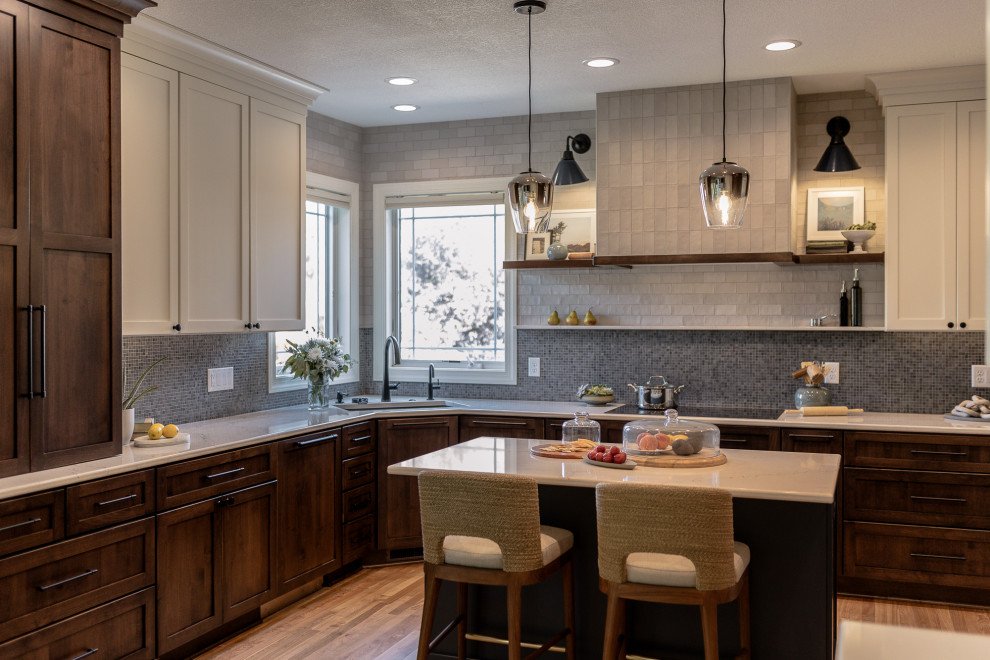 Inspiration for a mid-sized transitional l-shaped medium tone wood floor and brown floor eat-in kitchen remodel with an undermount sink, recessed-panel cabinets, dark wood cabinets, quartz countertops, blue backsplash, mosaic tile backsplash, stainless steel appliances, an island and white countertops