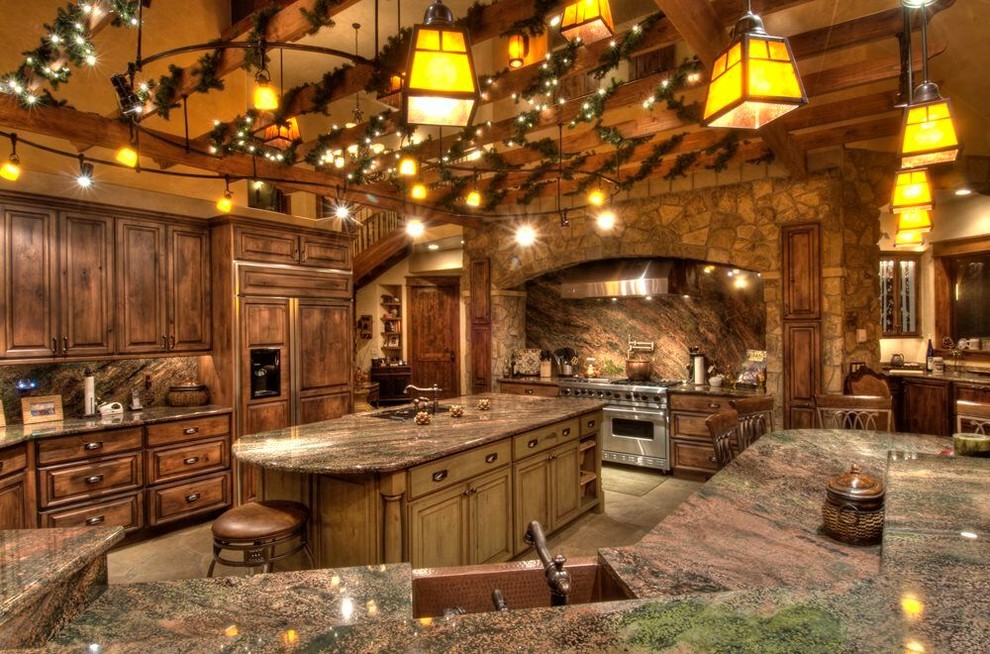 Example of a huge mountain style u-shaped cement tile floor and gray floor open concept kitchen design with a farmhouse sink, raised-panel cabinets, distressed cabinets, granite countertops, multicolored backsplash, stone slab backsplash, paneled appliances and an island