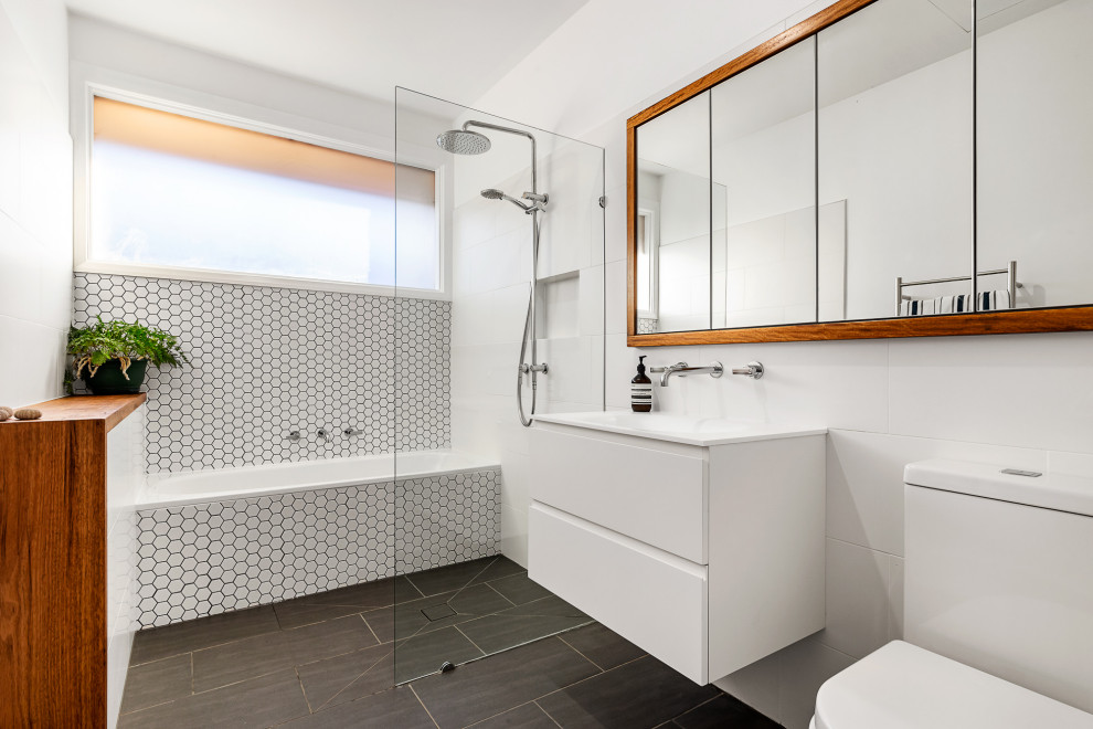 This is an example of a contemporary wet room bathroom in Melbourne with flat-panel cabinets, white cabinets, an alcove tub, white tile, white walls, an integrated sink, black floor, an open shower, white benchtops, a single vanity, a floating vanity and a niche.