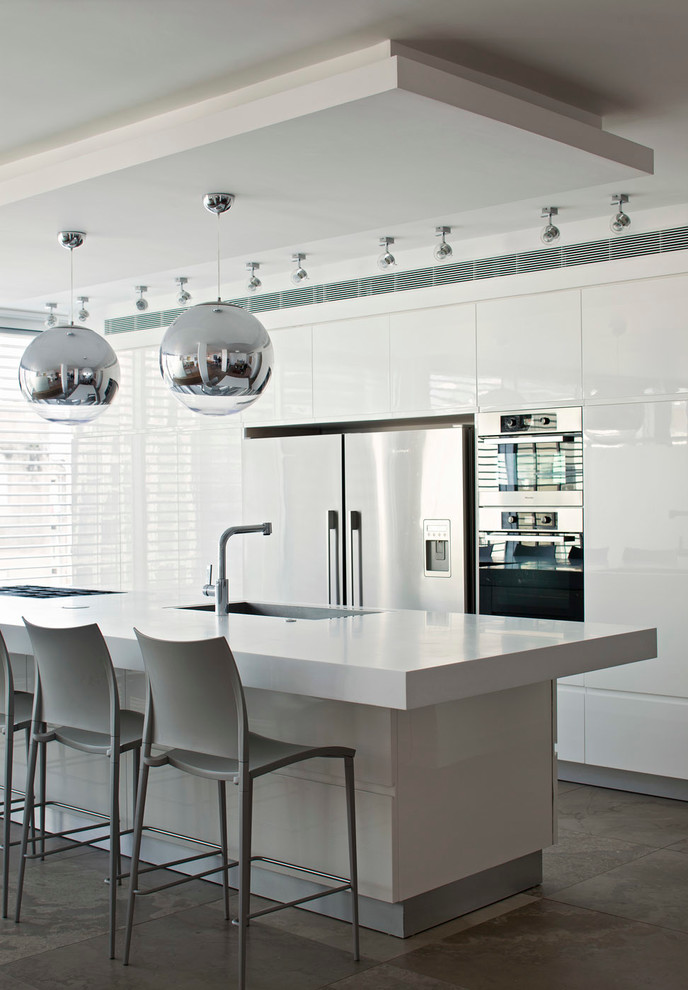 Mid-sized contemporary galley eat-in kitchen in Tel Aviv with an integrated sink, flat-panel cabinets, white cabinets, quartzite benchtops, stainless steel appliances and slate floors.