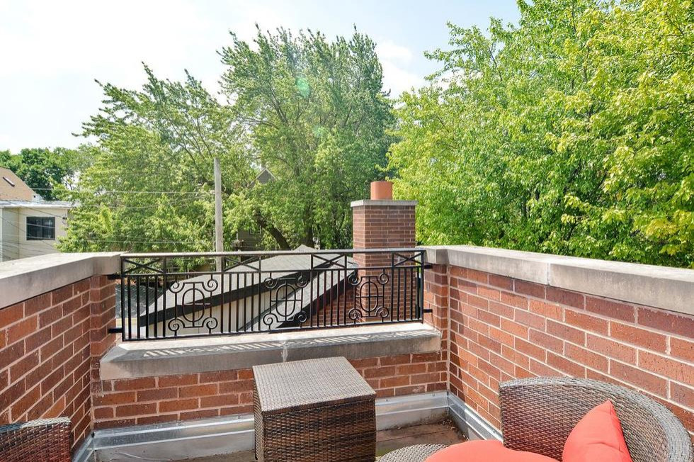 Mid-sized transitional rooftop deck in Chicago with with privacy feature, no cover and metal railing.