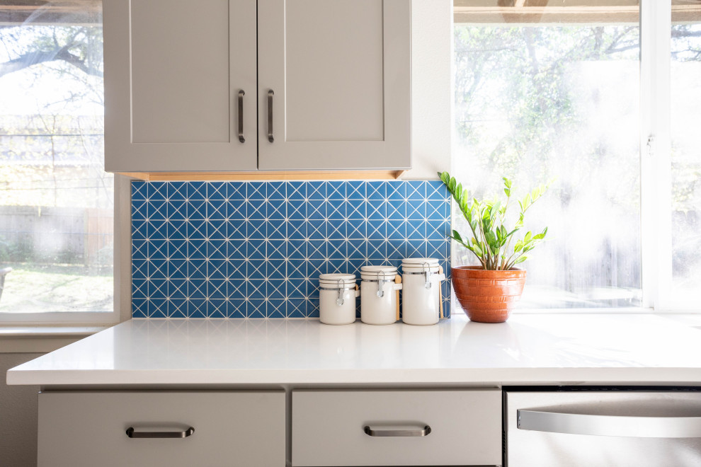 Inspiration for a mid-sized transitional u-shaped terrazzo floor and multicolored floor enclosed kitchen remodel in Austin with a double-bowl sink, shaker cabinets, gray cabinets, quartz countertops, blue backsplash, ceramic backsplash, stainless steel appliances, no island and white countertops