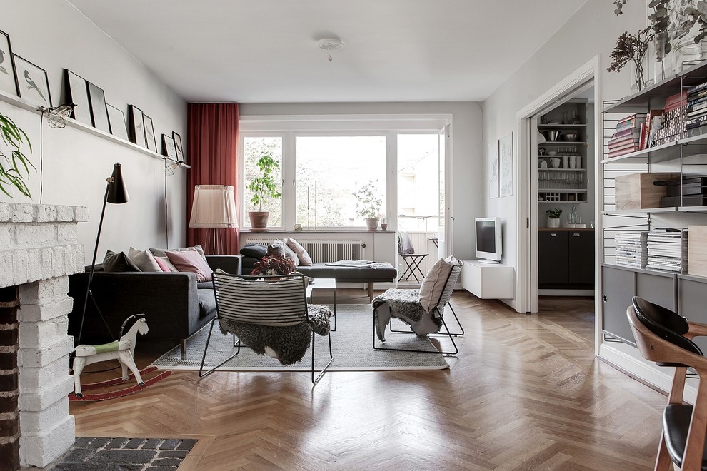 Mid-sized scandinavian enclosed living room in Malmo with white walls, medium hardwood floors and a freestanding tv.
