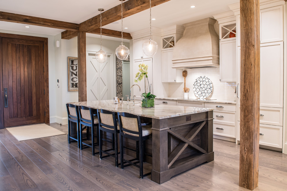 Country galley kitchen in St Louis with recessed-panel cabinets, beige cabinets, white splashback, subway tile splashback, with island, a farmhouse sink, white appliances and light hardwood floors.