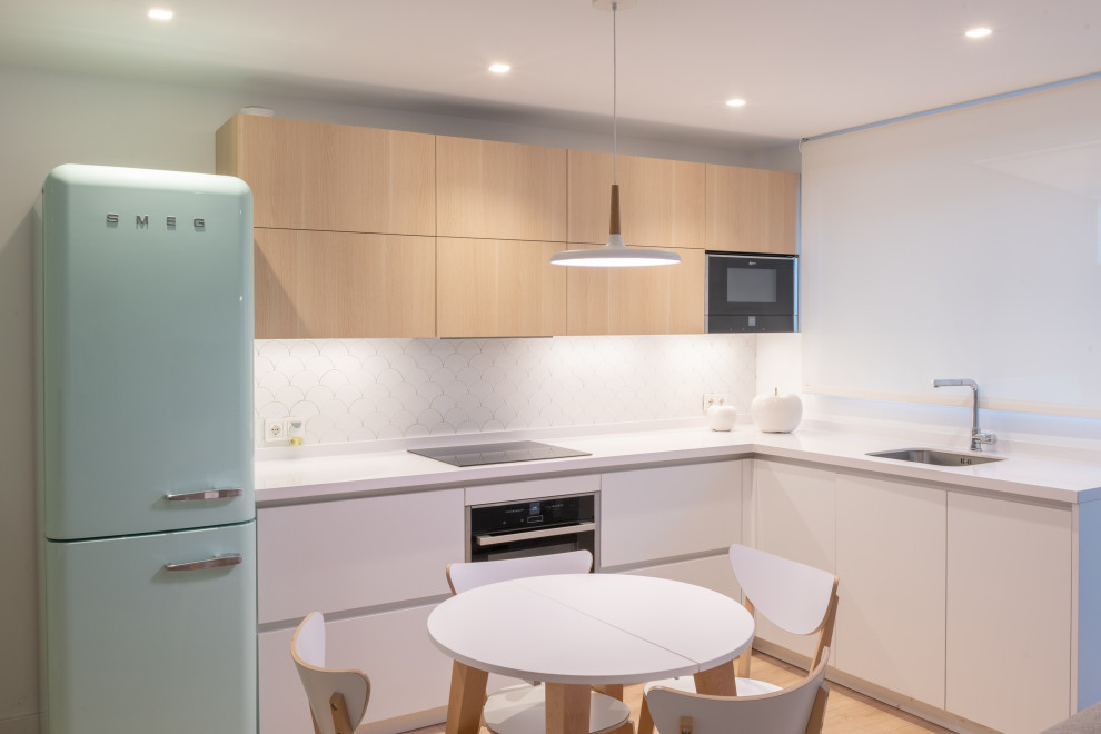 This is an example of a medium sized scandi l-shaped open plan kitchen in Other with a submerged sink, flat-panel cabinets, white cabinets, quartz worktops, white splashback, ceramic splashback, coloured appliances, medium hardwood flooring, no island, brown floors and white worktops.