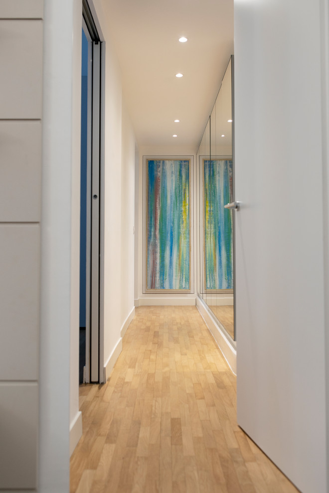 Foto de recibidores y pasillos modernos de tamaño medio con paredes blancas, suelo de madera clara, suelo beige, bandeja y papel pintado