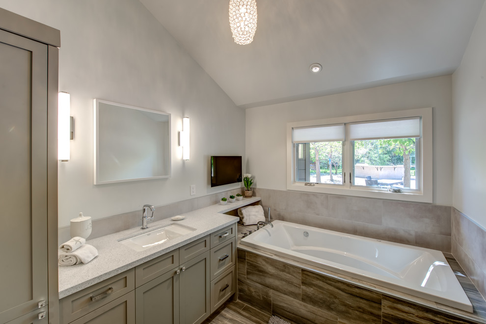 This is an example of a large contemporary master bathroom in San Francisco with an undermount sink, shaker cabinets, grey cabinets, engineered quartz benchtops, a freestanding tub, a corner shower, a one-piece toilet, porcelain tile, white walls and porcelain floors.