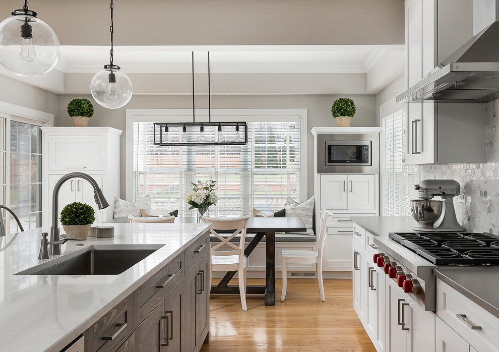 Inspiration for a large transitional light wood floor open concept kitchen remodel in Chicago with an undermount sink, shaker cabinets, white cabinets, quartz countertops, gray backsplash, marble backsplash, stainless steel appliances and an island