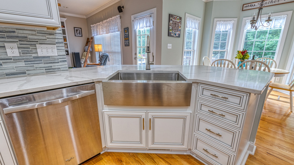 Example of a mid-sized medium tone wood floor kitchen design in Charlotte with a single-bowl sink, shaker cabinets, white cabinets, quartzite countertops, gray backsplash, glass tile backsplash, stainless steel appliances and white countertops