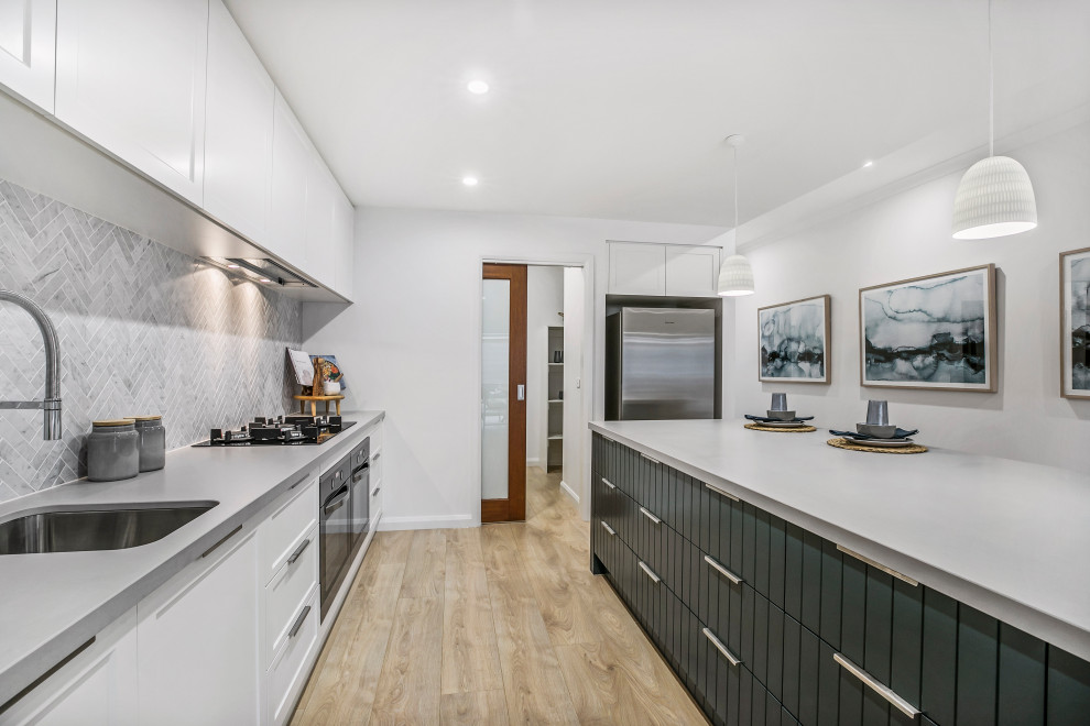Inspiration for a mid-sized contemporary single-wall open plan kitchen in Melbourne with an undermount sink, white cabinets, marble splashback, stainless steel appliances, with island and grey benchtop.