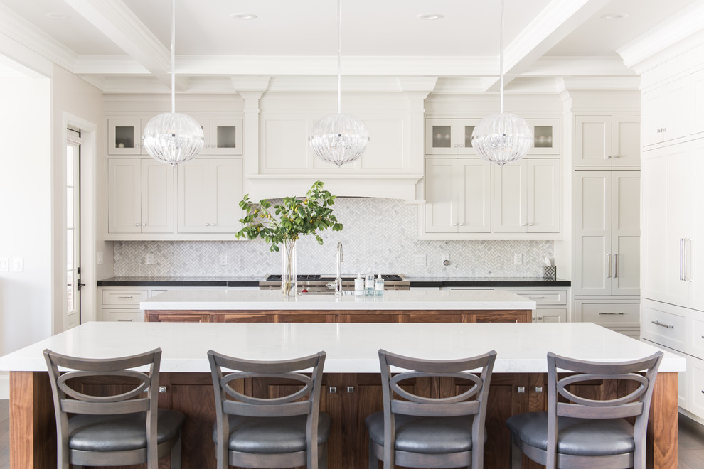 Transitional l-shaped kitchen in Salt Lake City with a farmhouse sink, shaker cabinets, beige cabinets, grey splashback, panelled appliances, multiple islands and white benchtop.