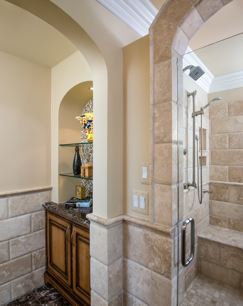 Photo of a large traditional master bathroom in Detroit with an undermount sink, beaded inset cabinets, distressed cabinets, limestone benchtops, a freestanding tub, an alcove shower, a one-piece toilet, beige tile, stone tile, beige walls, limestone floors, brown floor, a hinged shower door and brown benchtops.