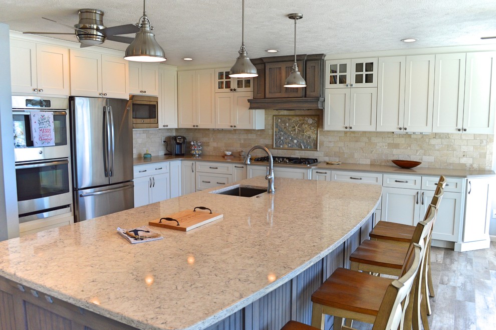 Inspiration for a large beach style l-shaped kitchen in Little Rock with with island, an undermount sink, shaker cabinets, white cabinets, granite benchtops, brown splashback, subway tile splashback, stainless steel appliances and brown floor.