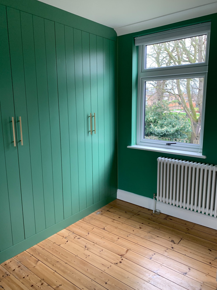 Aménagement d'une armoire encastrée contemporaine de taille moyenne avec un placard à porte plane, des portes de placards vertess et un sol en bois brun.