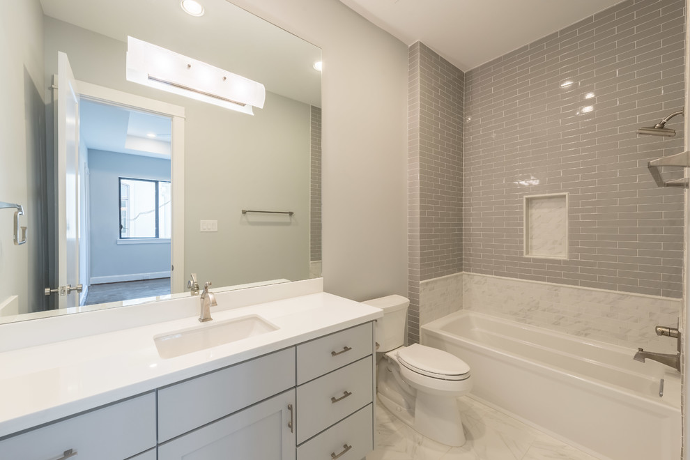 Large transitional kids bathroom in Houston with an undermount sink, shaker cabinets, grey cabinets, marble benchtops, an alcove shower, a one-piece toilet, gray tile, porcelain tile, grey walls and porcelain floors.