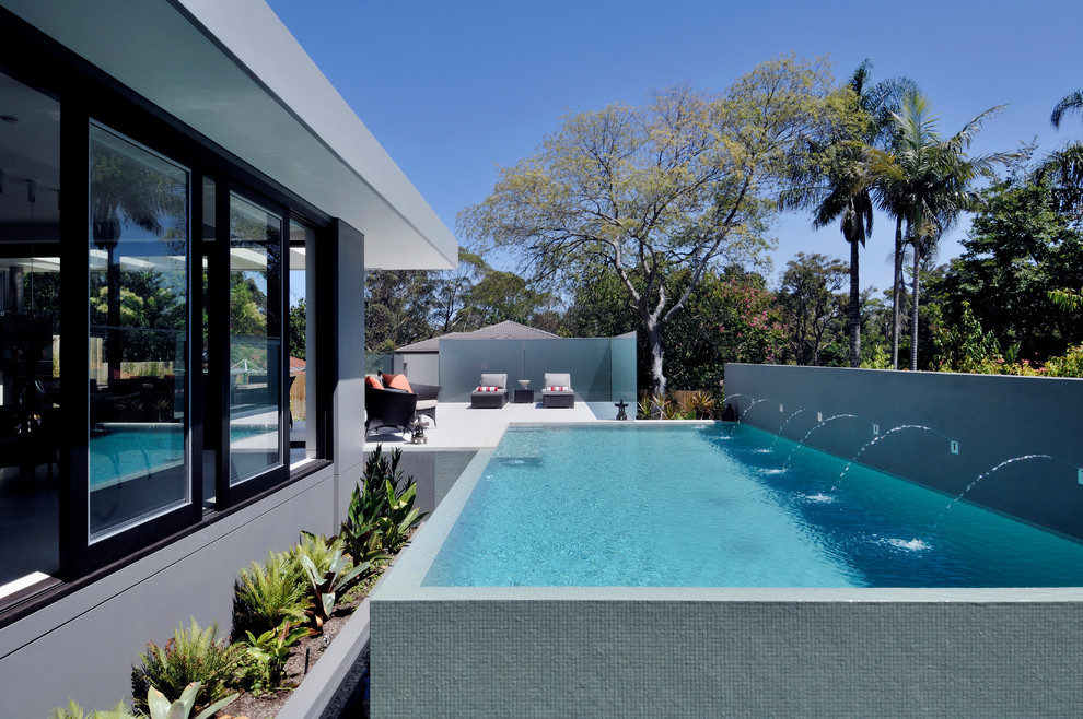 This is an example of a contemporary rectangular aboveground pool in Sydney with a water feature.
