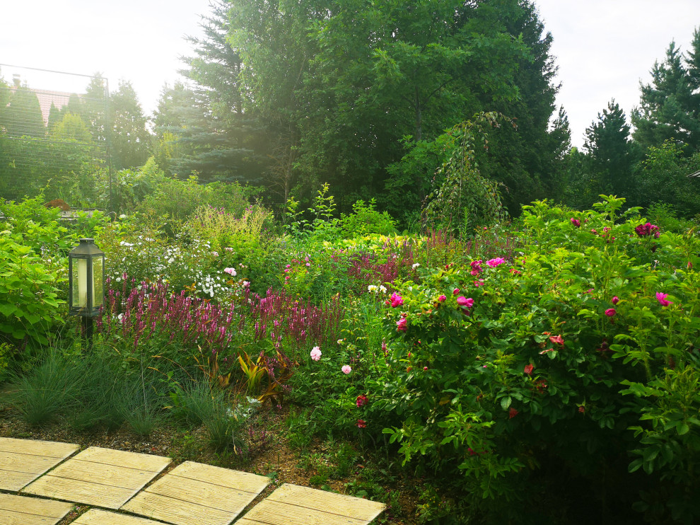 Cette photo montre un xéropaysage arrière de taille moyenne et l'été avec un massif de fleurs, une exposition ensoleillée, des pavés en béton et une clôture en bois.