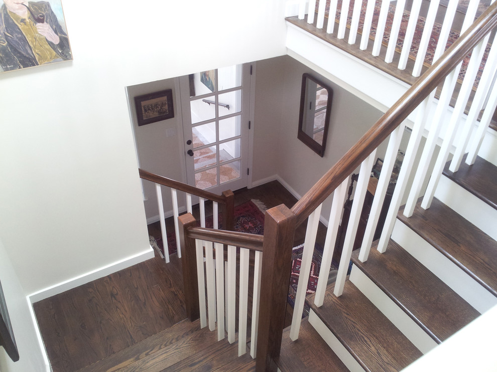 This is an example of a beach style wood u-shaped staircase in Los Angeles with painted wood risers and wood railing.