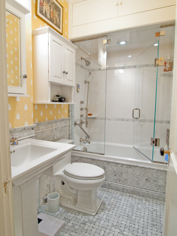 Photo of a traditional bathroom in Boston with a pedestal sink, an alcove tub, a shower/bathtub combo, a two-piece toilet, white tile, yellow walls and mosaic tile floors.