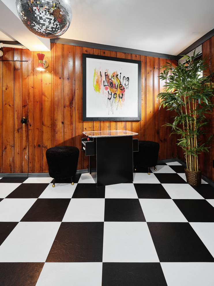 This is an example of a bohemian fully buried basement in New York with a game room, brown walls, vinyl flooring, multi-coloured floors and panelled walls.
