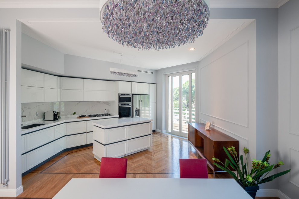This is an example of a large contemporary l-shaped open plan kitchen in Rome with a single-bowl sink, raised-panel cabinets, white cabinets, quartz benchtops, white splashback, porcelain splashback, stainless steel appliances, light hardwood floors, with island, white benchtop and recessed.