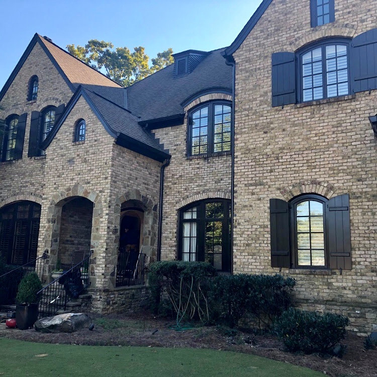 This is an example of a large traditional brick brown house exterior in Atlanta with four or more storeys, a gable roof and a shingle roof.