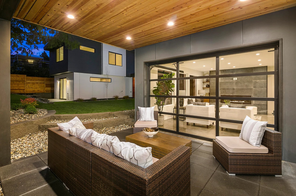 Foto di un grande patio o portico minimal dietro casa con cemento stampato, un tetto a sbalzo e un focolare
