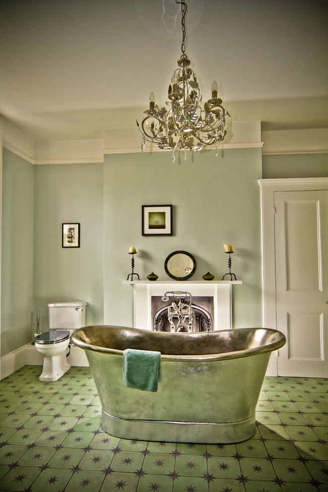 This is an example of a traditional bathroom in Sussex with a freestanding tub, a two-piece toilet, green walls and green floor.