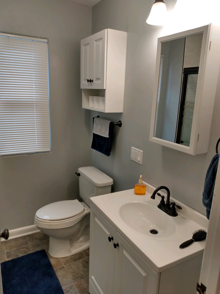 Photo of a mid-sized contemporary 3/4 bathroom in Other with raised-panel cabinets, white cabinets, an alcove shower, a two-piece toilet, grey walls, linoleum floors, an integrated sink, solid surface benchtops, brown floor, a sliding shower screen, white benchtops, a single vanity and a freestanding vanity.