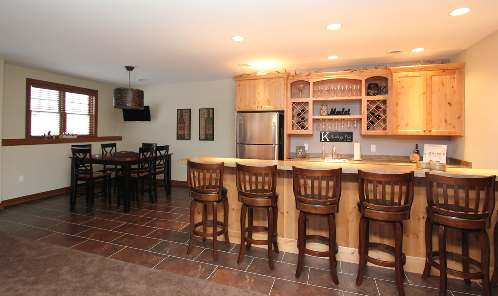 Photo of a large country galley seated home bar in Milwaukee with a drop-in sink, shaker cabinets, light wood cabinets, granite benchtops and laminate floors.