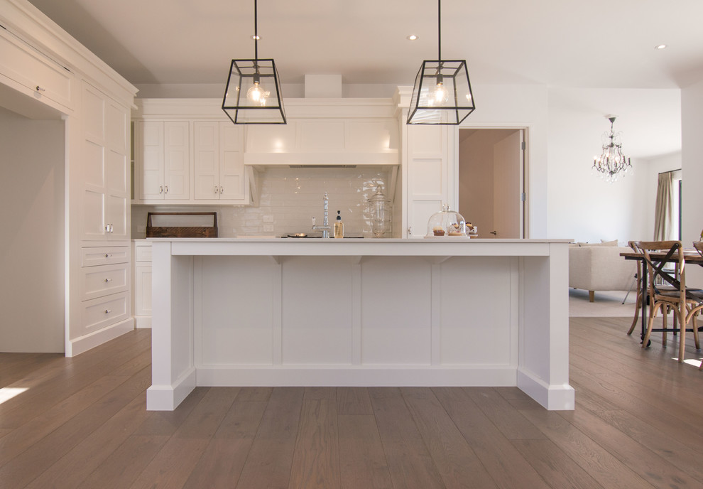 Design ideas for a mid-sized modern galley eat-in kitchen in Other with light hardwood floors, beige floor, louvered cabinets, white cabinets, white splashback, ceramic splashback, white appliances and with island.