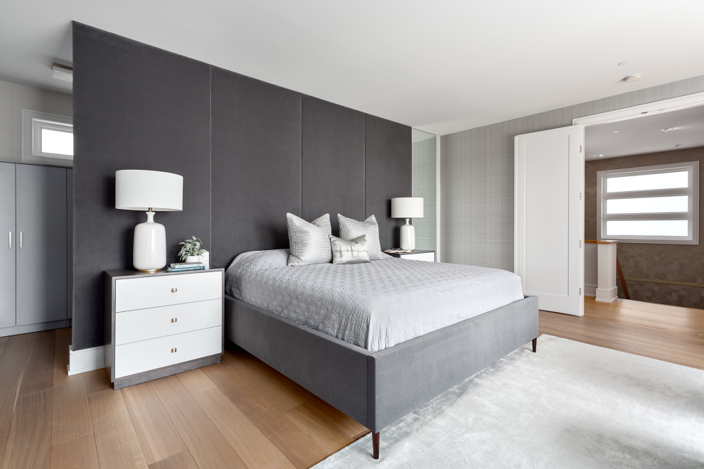 Large beach style master bedroom in Vancouver with grey walls, medium hardwood floors and brown floor.