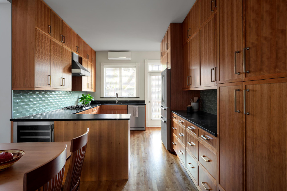 Photo of a large contemporary galley kitchen/diner in DC Metro with a submerged sink, shaker cabinets, medium wood cabinets, engineered stone countertops, blue splashback, ceramic splashback, stainless steel appliances, medium hardwood flooring, a breakfast bar, brown floors and black worktops.