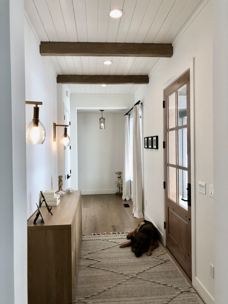 Mittelgroßes Landhaus Foyer mit weißer Wandfarbe, hellem Holzboden, Einzeltür, heller Holzhaustür, freigelegten Dachbalken und Holzdielenwänden in Sonstige