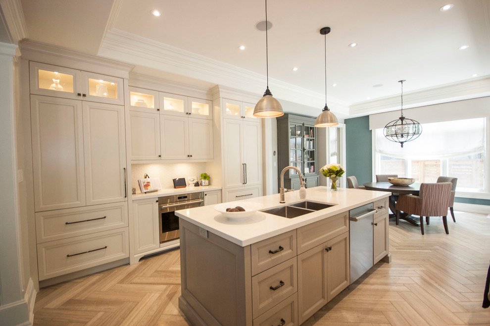 Large transitional galley eat-in kitchen in Toronto with a double-bowl sink, shaker cabinets, white cabinets, quartzite benchtops, white splashback, ceramic splashback, stainless steel appliances, ceramic floors and with island.