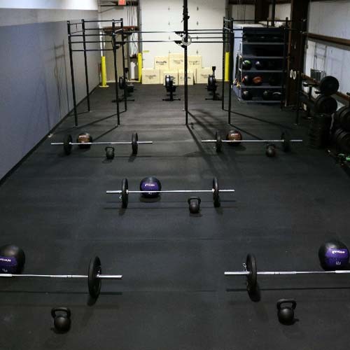 Expansive industrial home weight room in Chicago with white walls and black floor.