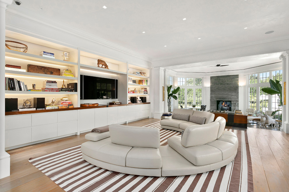 Inspiration for a transitional open concept family room in New York with white walls, medium hardwood floors, a built-in media wall and brown floor.