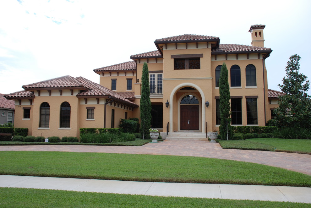 Expansive mediterranean two-storey stucco yellow exterior in Orlando with a gable roof.