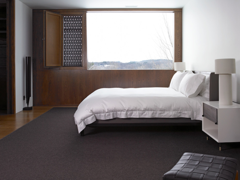 This is an example of a mid-sized contemporary bedroom in New York with white walls and medium hardwood floors.