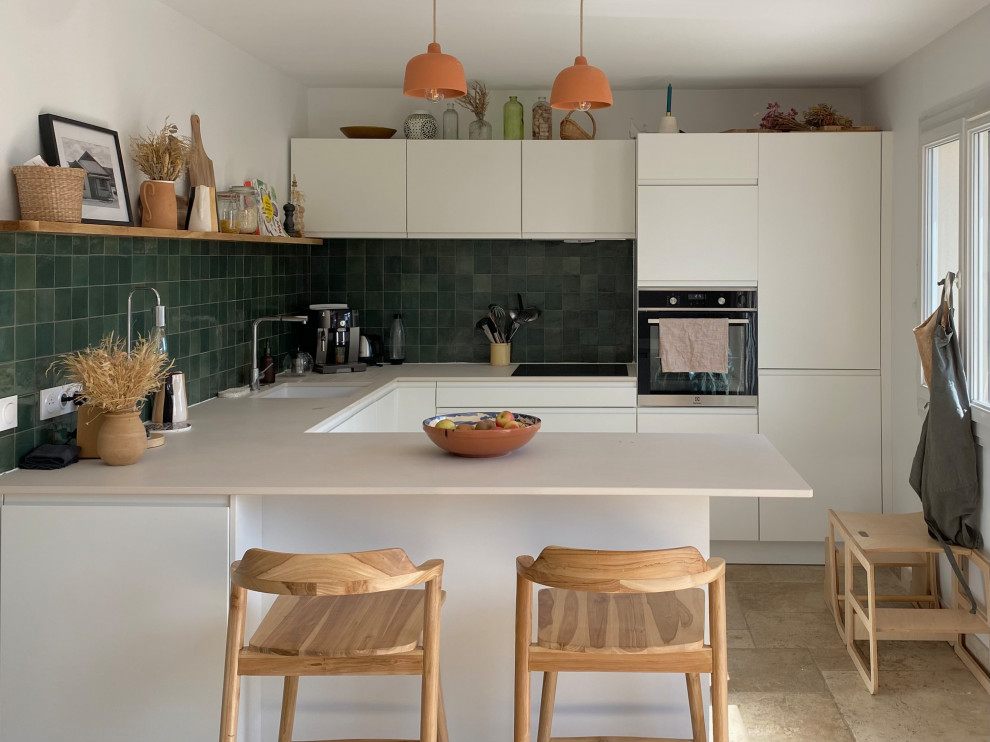Mid-sized contemporary u-shaped open plan kitchen in Marseille with a single-bowl sink, white cabinets, green splashback, travertine floors and beige floor.